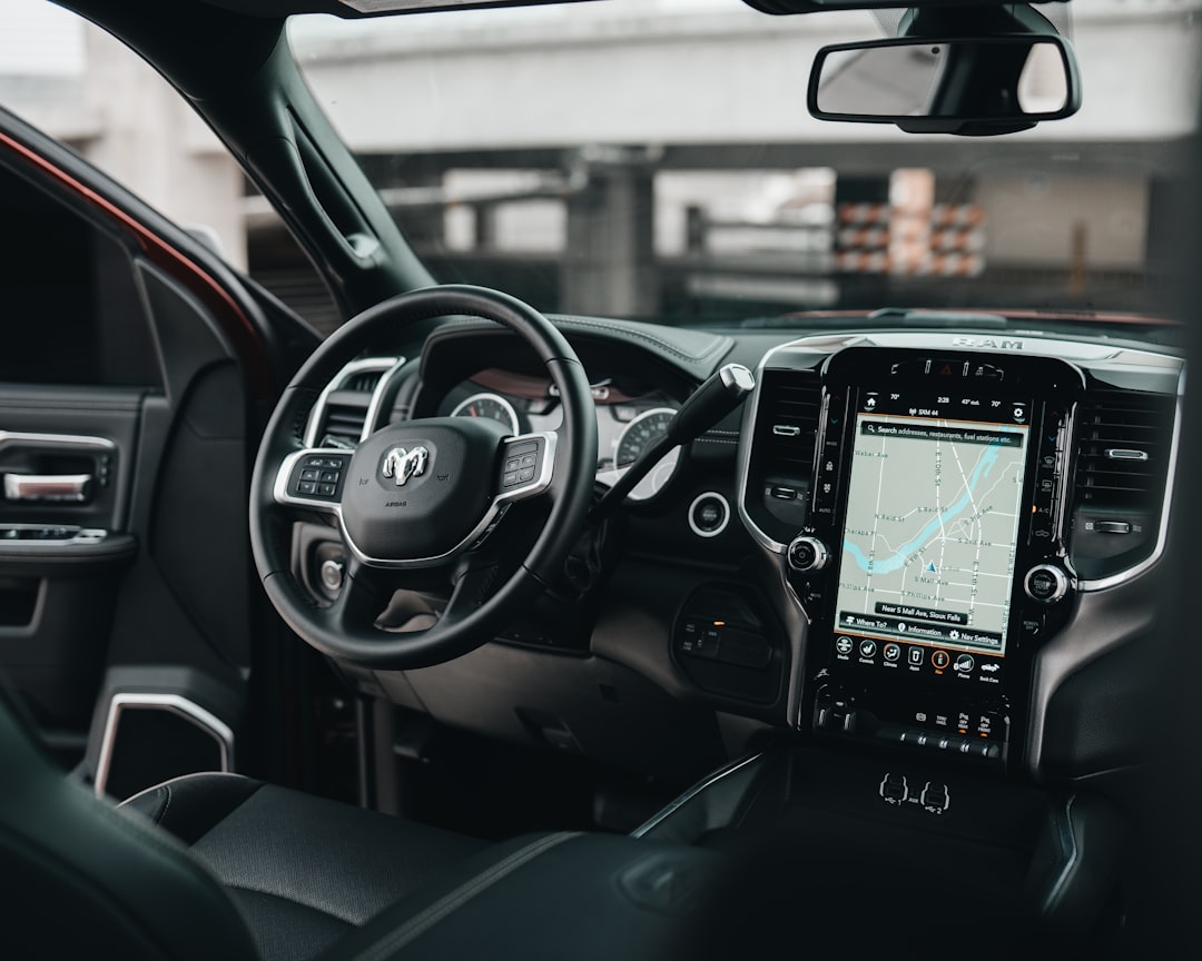 Dodge Ram truck interior featuring black leather upholstery, a modern touchscreen display showing a map, and sleek dashboard controls with a prominent steering wheel.
