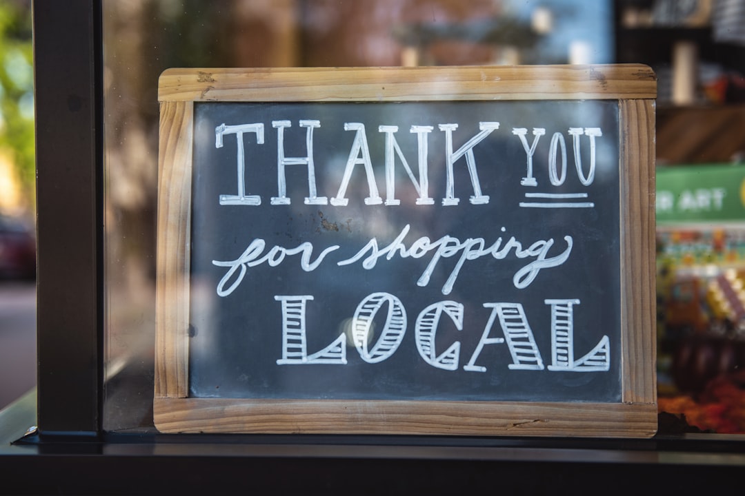 Chalkboard sign with wooden frame features the message 'Thank you for shopping local' in white chalk, promoting community spirit and local businesses.