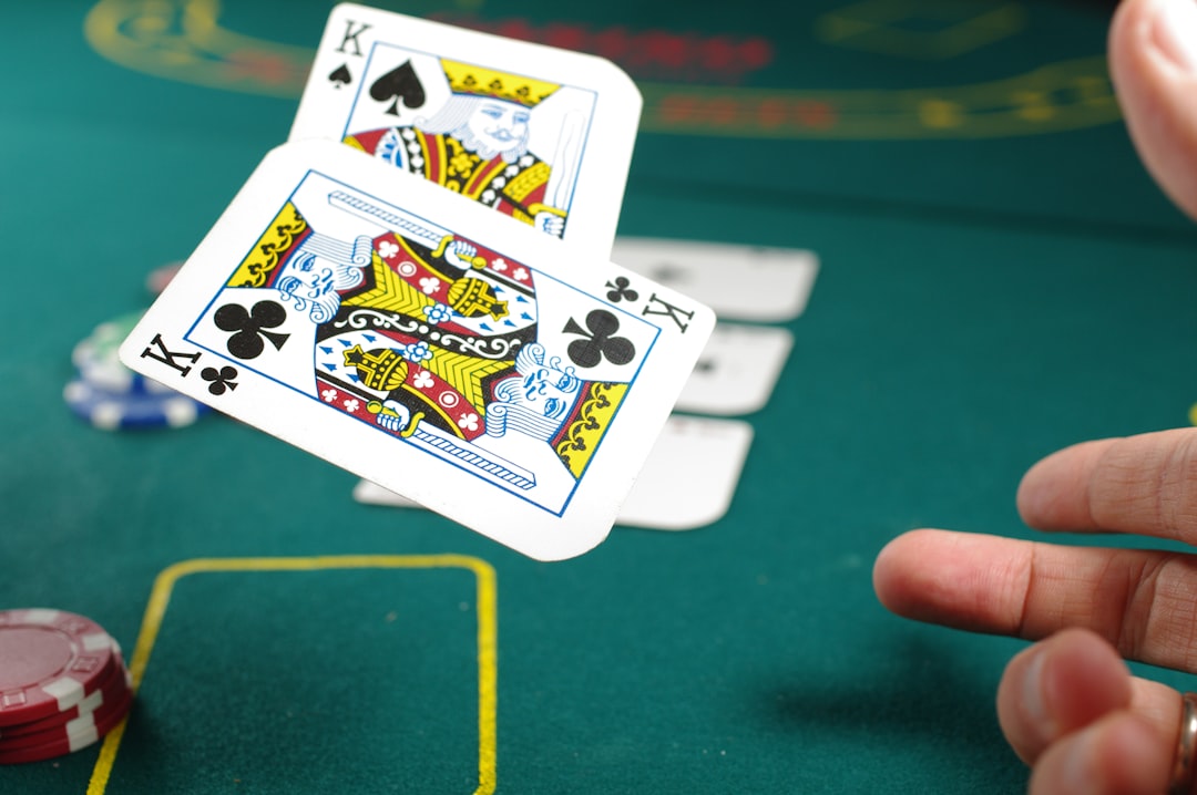 Cards floating over a green poker table, poker chips, and a hand reaching out, amidst other playing cards and a kings' cards, a poker scene.